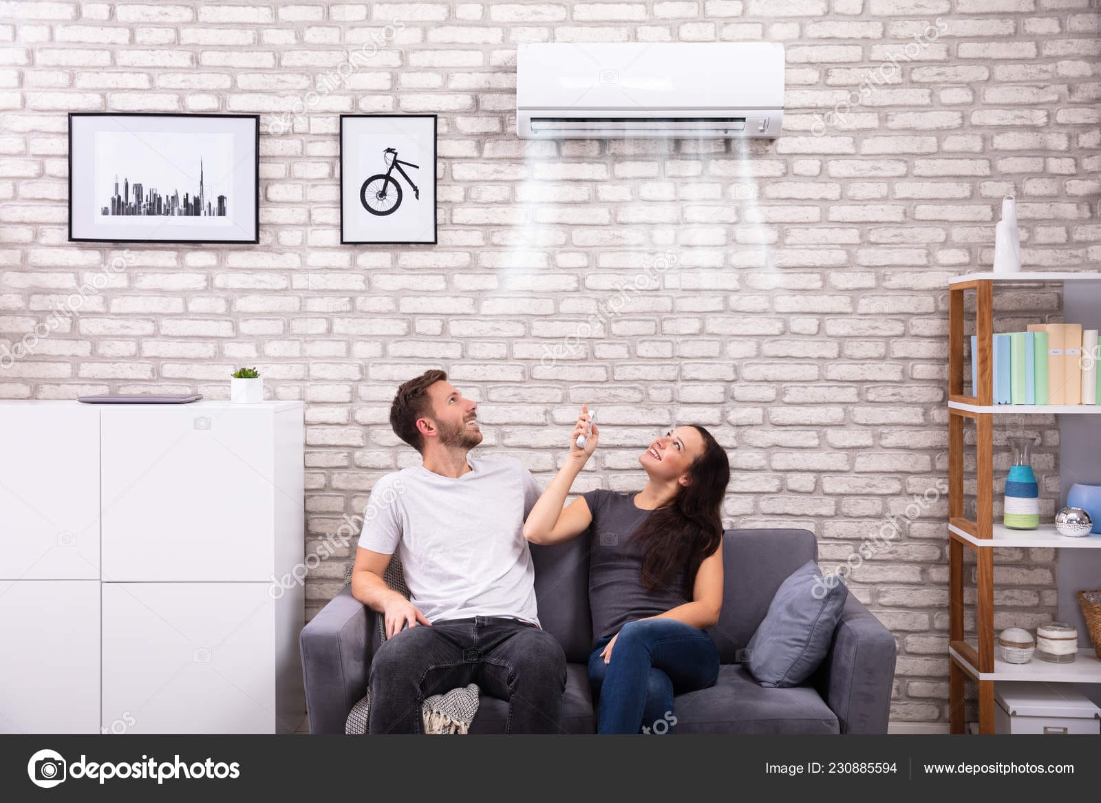 Happy Couple Operating Air Conditioner At Home
